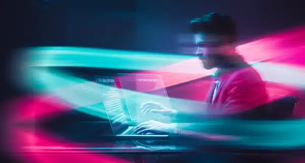 Hombre escribiendo en pantalla holográfica rodeado de ondas de luz veloces